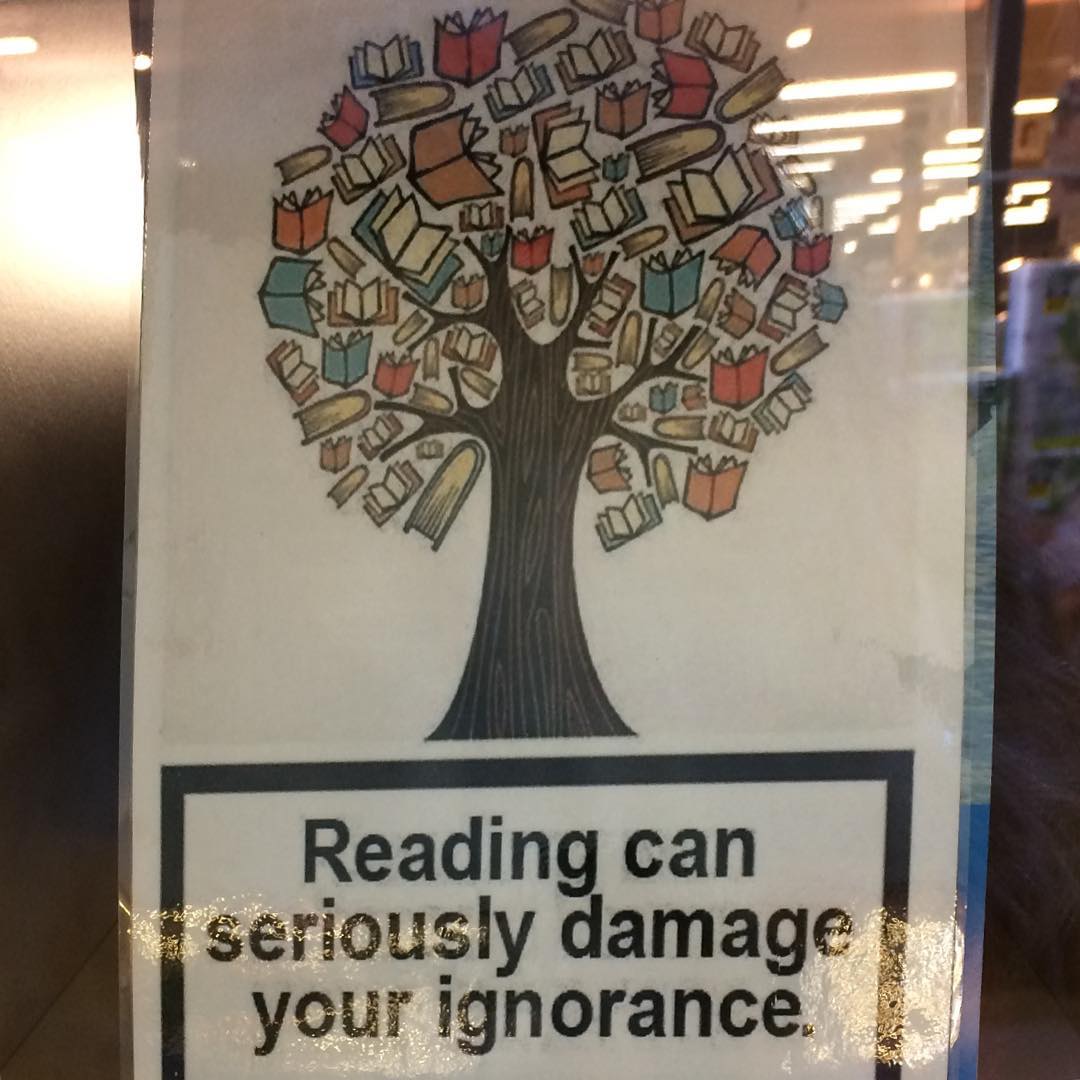 Gemalter Baum mit Büchern als Blätter auf Plakat. Darunter der Text: Lesen kann ernsthaft Ihre Intoleranz gefährden.
